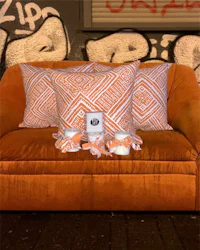 an orange couch with pillows in front of a graffiti wall