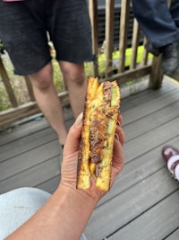 a person holding a sandwich on a deck