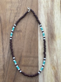 a brown and turquoise beaded necklace on a wooden table