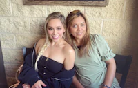 two women posing for a picture in front of a brick wall