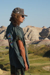 a man in a hat is standing in the middle of a desert