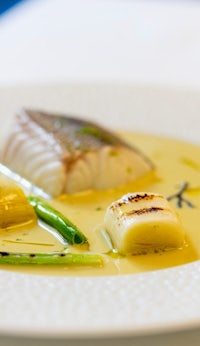 a white plate with fish and vegetables on it