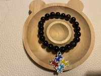 a black beaded bracelet with a teddy bear charm