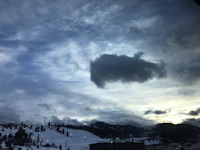 a cloud in the sky over a snow covered mountain