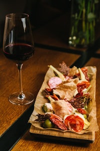 a plate of meat and wine on a wooden table