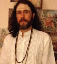 a man with long hair standing in front of a wall