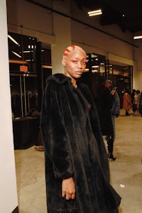 a woman in a fur coat standing in front of a crowd