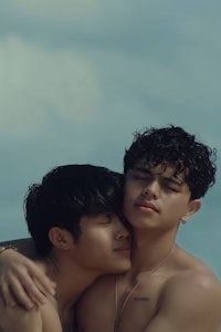 two shirtless men hugging each other on the beach