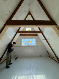 a man is standing in an attic with wooden beams
