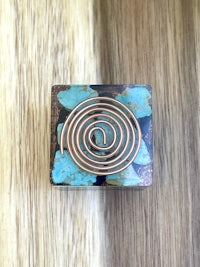 a copper and turquoise spiral box on a wooden table
