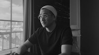 a black and white photo of a man sitting in front of a window
