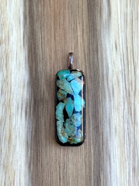 a turquoise stone pendant on a wooden surface