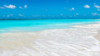 a sandy beach with blue water and white sand