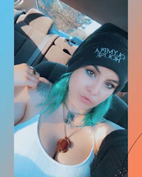 a woman in a car with blue hair and a beanie