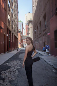 a woman in a black dress standing on a street
