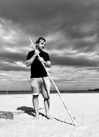 a man standing on a beach holding a stick