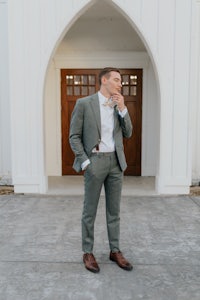 a man in a gray suit standing in front of a church