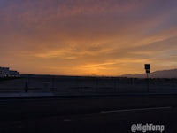 a sunset over a parking lot with a street sign in the background