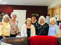 a group of older women posing for a picture in a living room