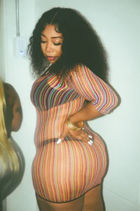 a woman in a striped dress posing in a bathroom