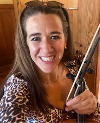 a woman in a leopard print shirt is smiling while holding a violin