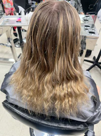 a woman's hair in a salon chair with long wavy hair