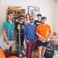 a group of people standing in a living room with a guitar