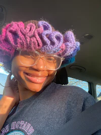 a woman in a car wearing a crocheted hat