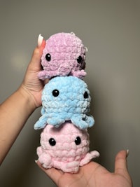 three pink and blue stuffed animals in a person's hands