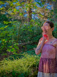 a woman in a pink dress standing in a wooded area