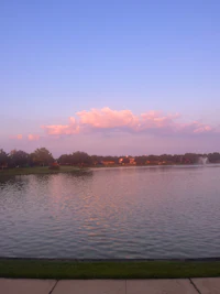 a lake at dusk with clouds in the sky