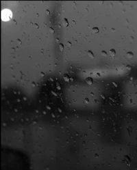 a black and white photo of rain drops on a window