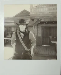a man in a cowboy hat is standing in front of a building