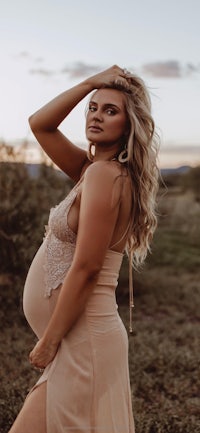 a pregnant woman posing in a field at sunset