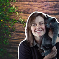 a woman holding a black cat in front of a wooden background