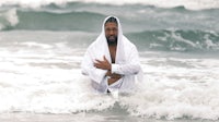 a man in a white robe sitting in the ocean