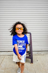 a young girl wearing sunglasses and a blue t - shirt