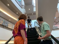 a group of people walking up an escalator in a mall
