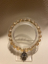 a clear glass holder with a hamsa bead on it
