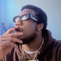 a man wearing sunglasses smoking a cigarette