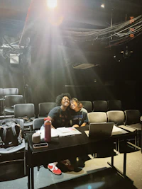 two people sitting at a table in an auditorium