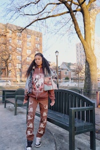 a woman is standing on a park bench wearing a hoodie and sweatpants