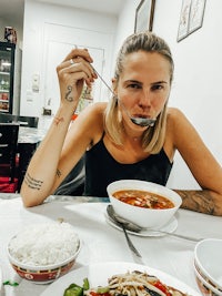 a woman sitting at a table with a bowl of food