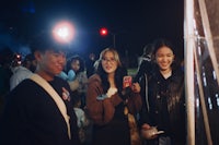 a group of people standing in front of a tent at night