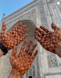 two people with their hands painted with checkered patterns in front of the taj mahal