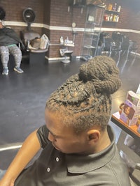 a boy is getting his hair braided in a salon