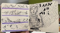 a notebook with a drawing of a mountain and mountains