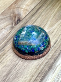 a blue and green glass sphere on a wooden table