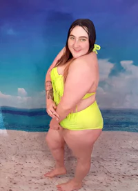 a woman in a yellow bikini posing on the beach