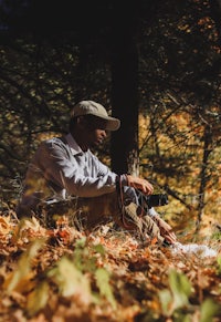 a man sitting in the woods with a camera